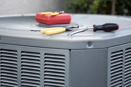Technician’s tools resting on top of an outdoor AC unit during a repair