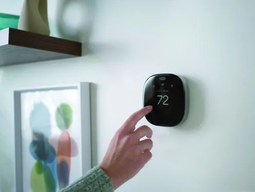 Hand adjusting a smart thermostat set to 72 degrees